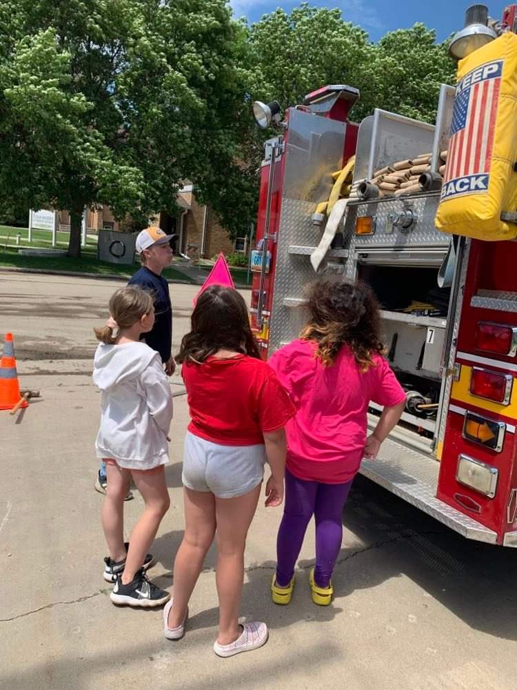 the kids looking at the hoses on the firetruck.