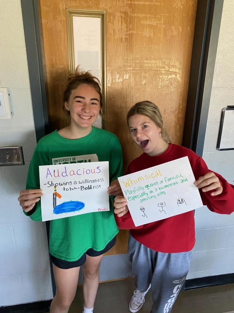 2 girls with vocabulary word posters.