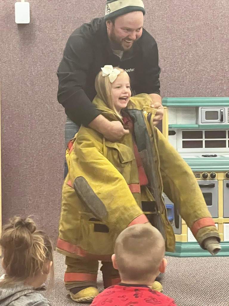 A firefighter putting on a firefighters jacket.