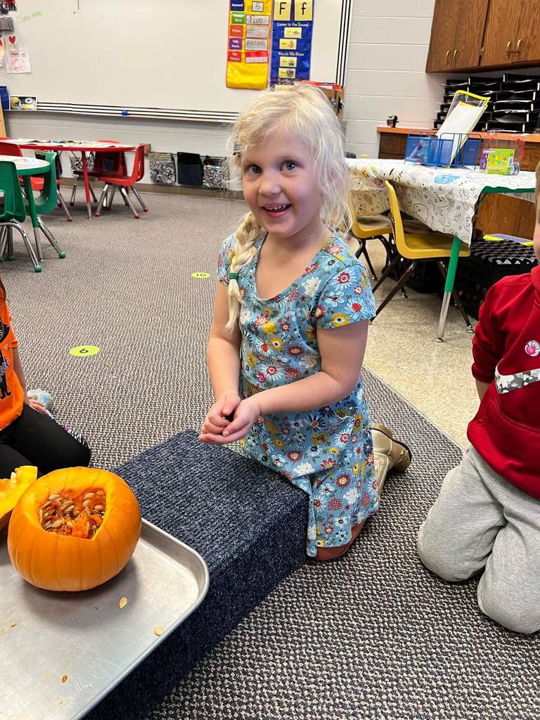 A student touching the seeds of a pumpkin.