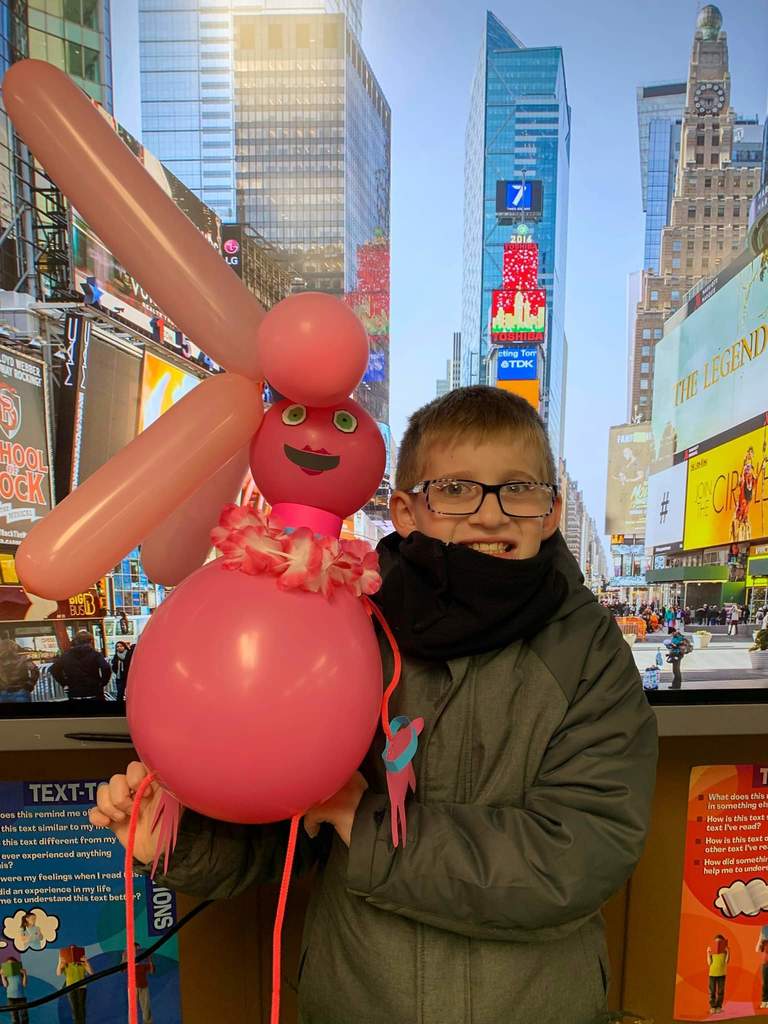 A boy holding his pink character balloon.