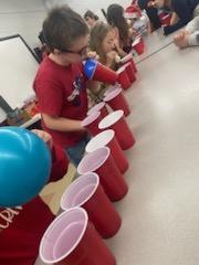Kids stacking cups with balloons.