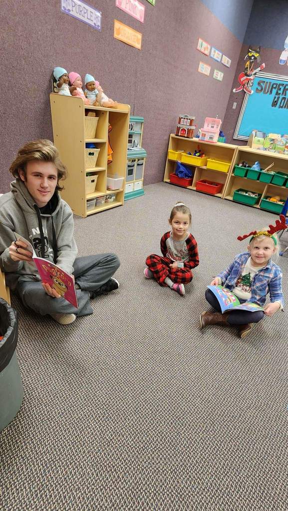 A boy reading books to kids.