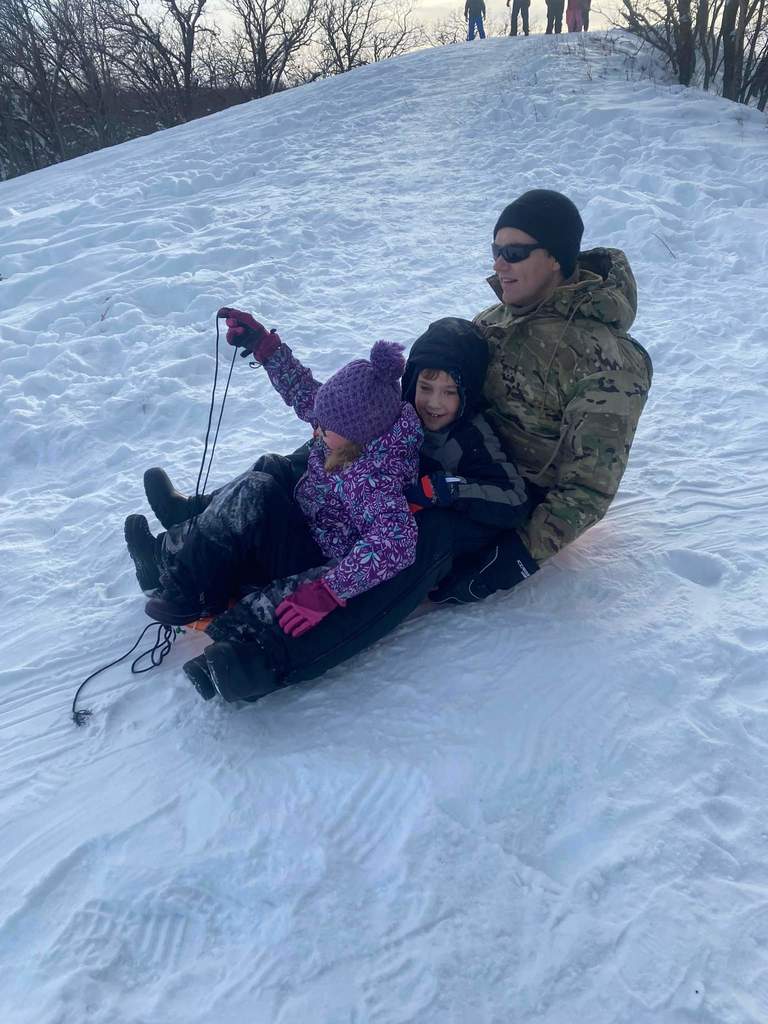 A dad sledding with his kids.