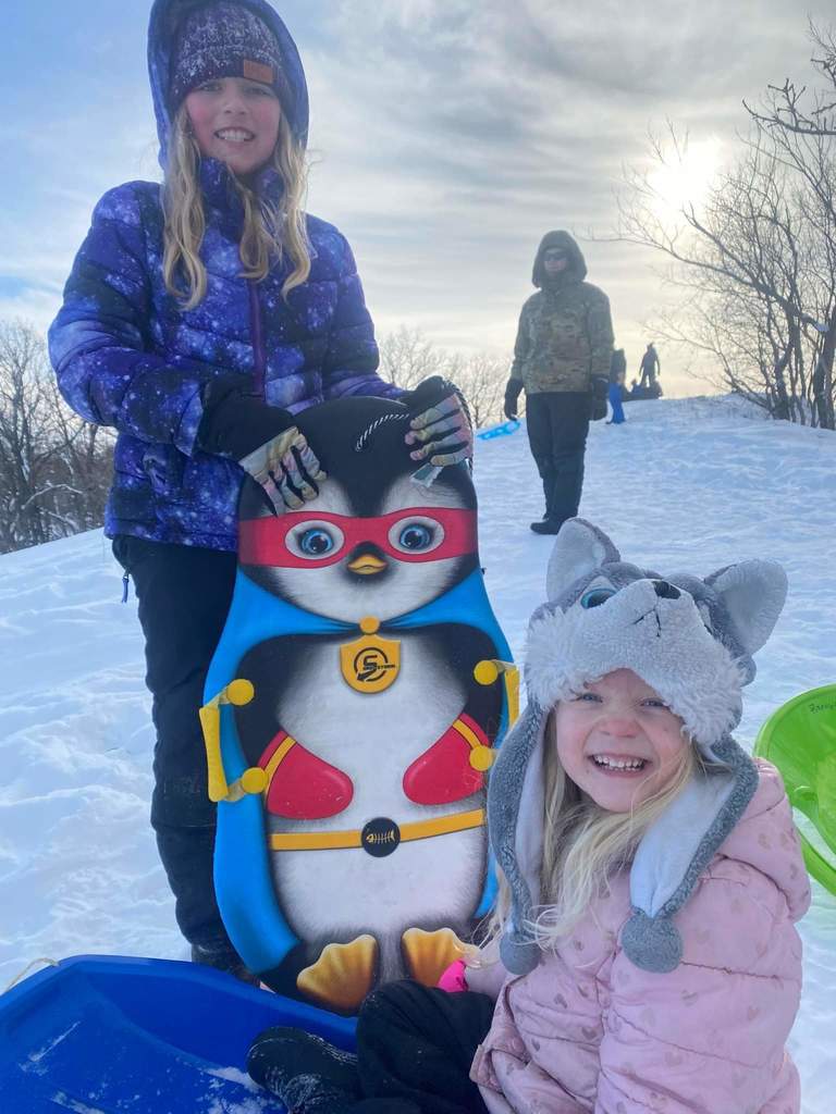 2 girls holding their sled.