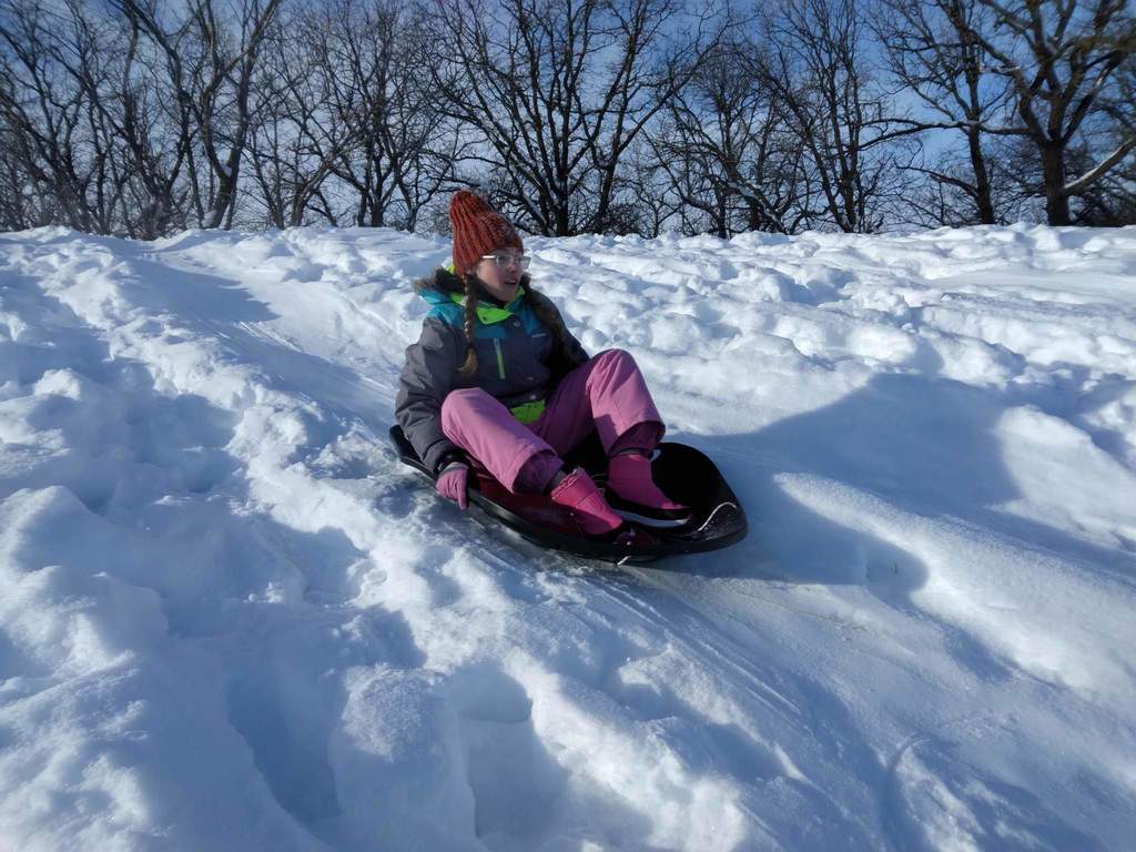 A girl sledding down the hill.