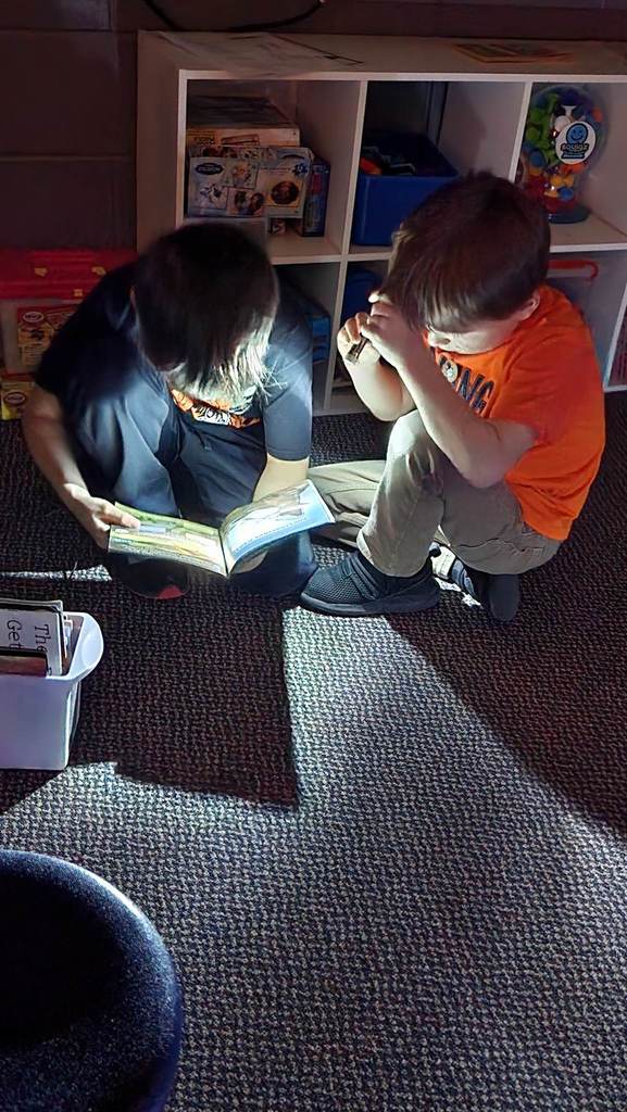2 boys reading books with flashlights