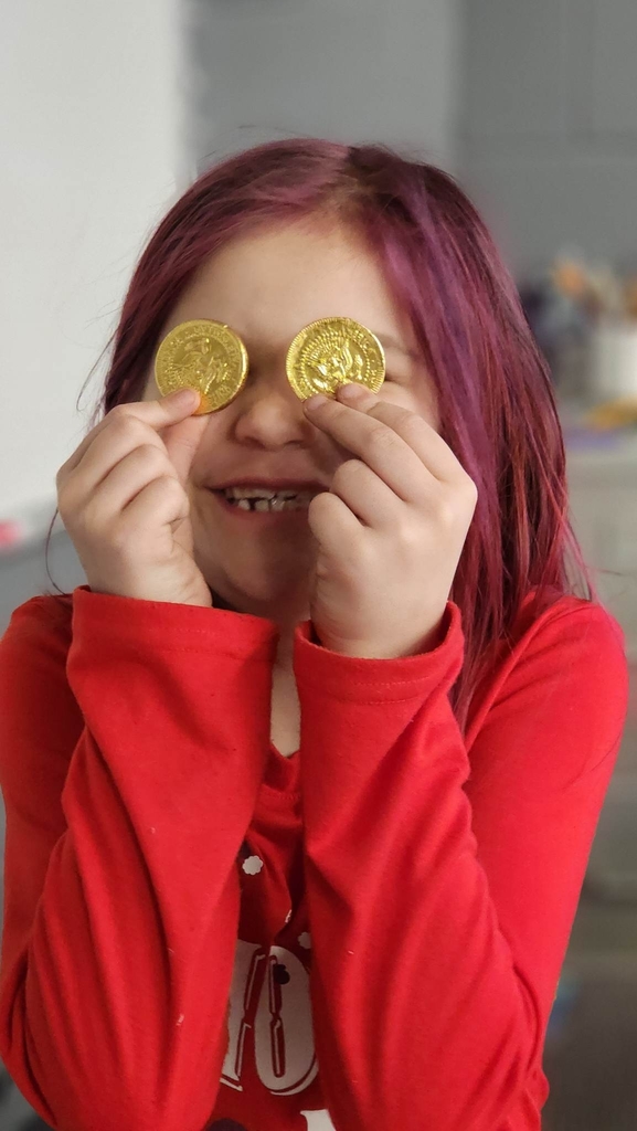 a girl holding gold coins on her face