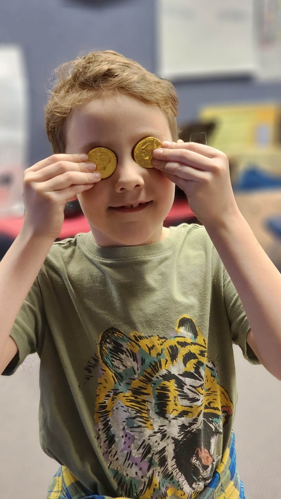 a boy holding gold coins over his eyes
