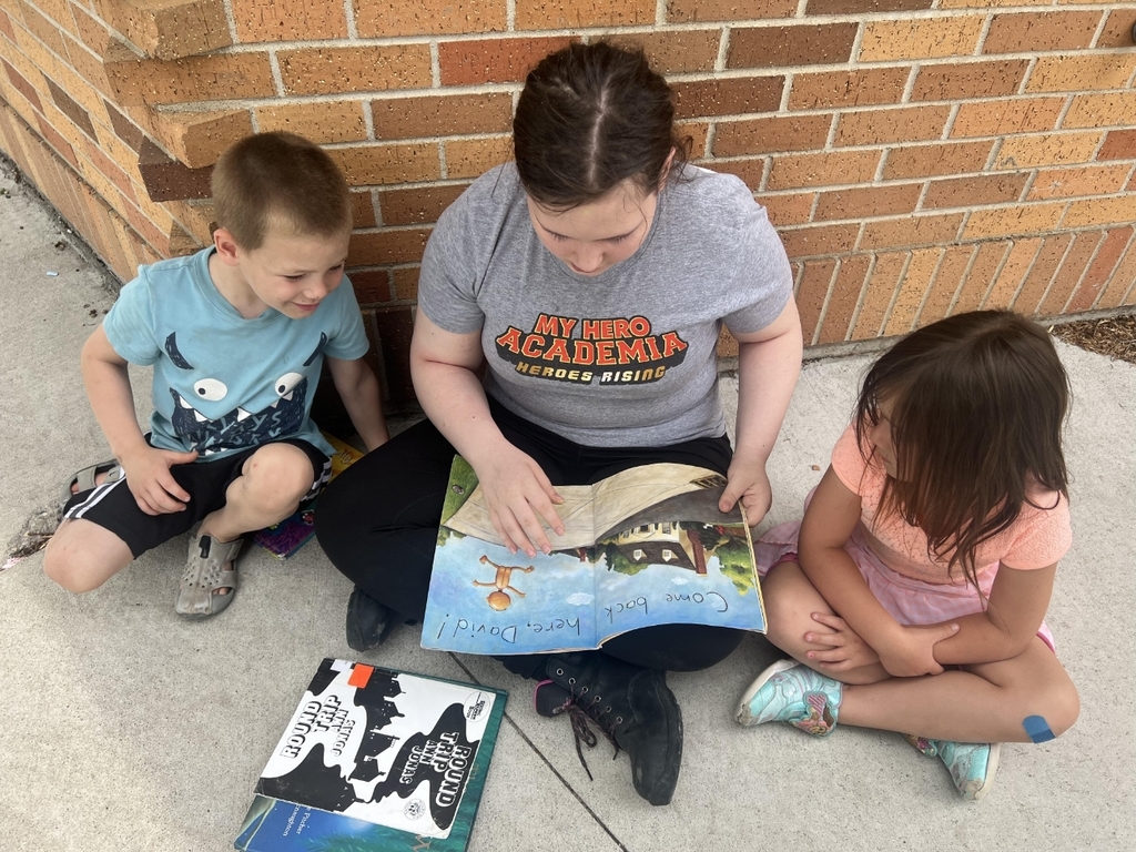a girl reading to 2 kids