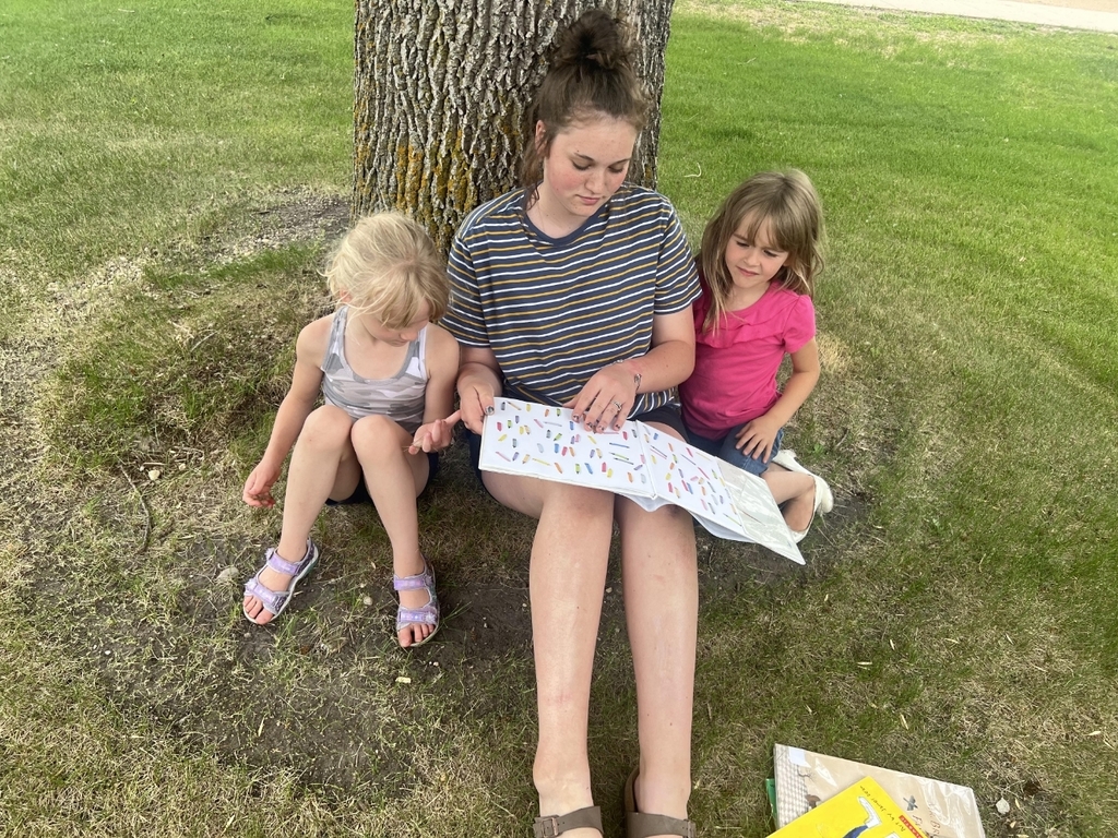 a girl reading to 2 kids